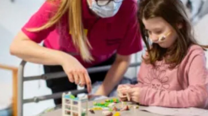 Chemo patient playing with lego alongside a health play specialist